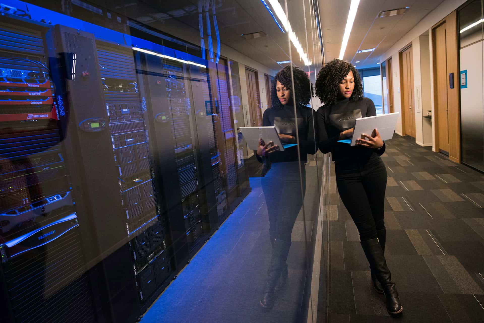 Woman Leaning against the IT room door with laptop checking on a system